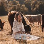 Die Hofbestizerin sitzt in Mitten von Kühen